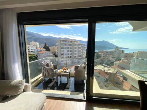 View from the room onto a furnished balcony with seating furniture and a view of the city and sea. - image 13