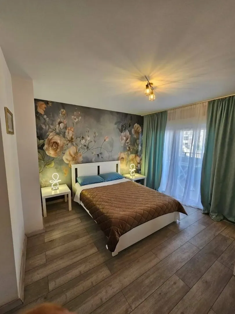 Furnished bedroom with a double bed, feature wall wallpaper, and access to the terrace.