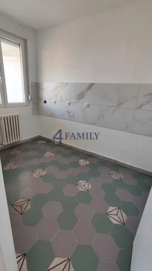 Prazna prostorija predviđena za kuhinju sa pločicama i radijatorom.