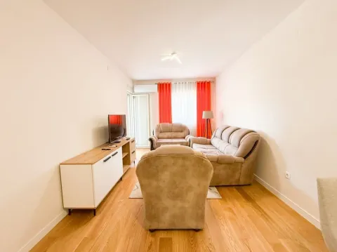 Living room with seating furniture, TV unit, and hardwood flooring. - image 2
