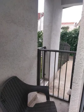 Covered terrace with a black plastic chair and a view of the yard. - image 4