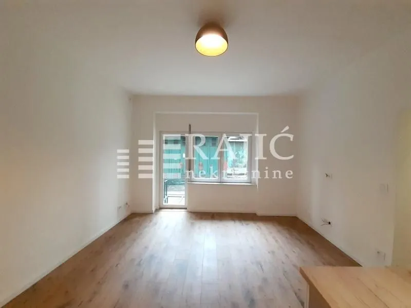 Empty living room with wooden flooring and access to a terrace.