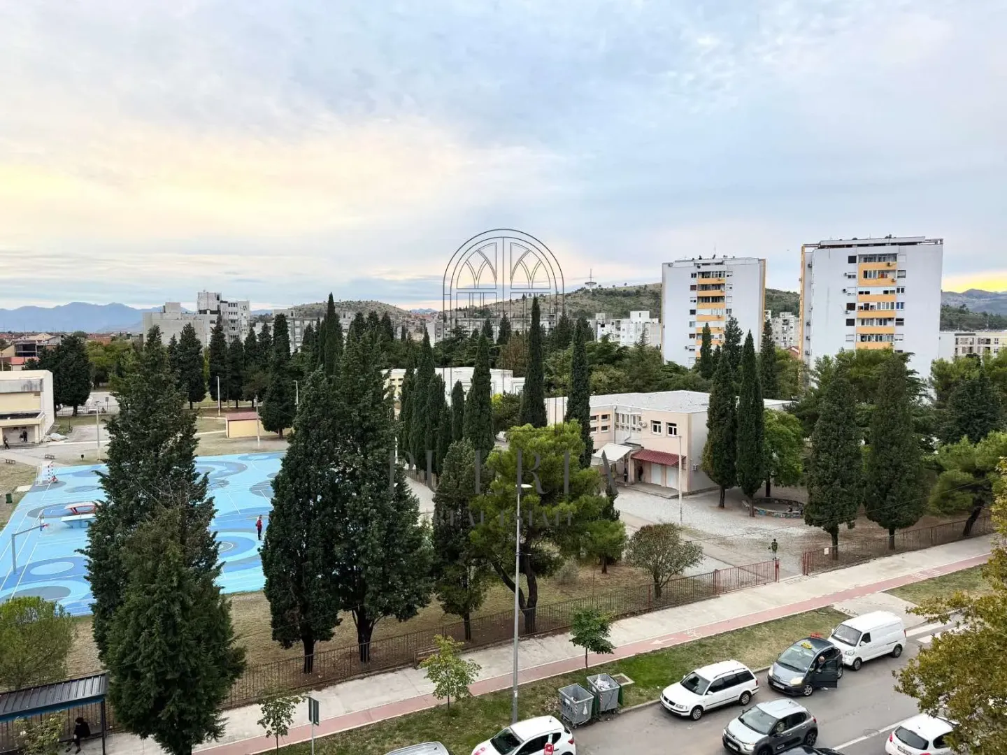 Pogled sa terase na gradsko naselje, zelene površine i ulicu.