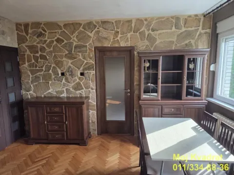Trpezarija sa drvenim nameštajem i zidom obloženim kamenom. - image 2