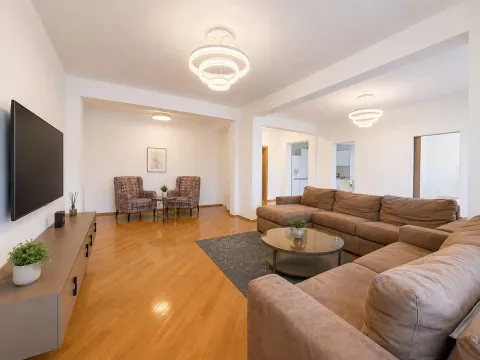 Spacious and bright living room with a sofa set and television. - image 5