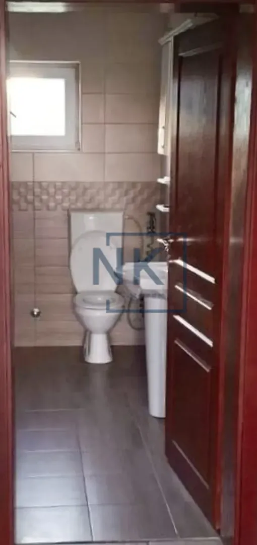 Small bathroom with a toilet, washbasin, and tiled walls.