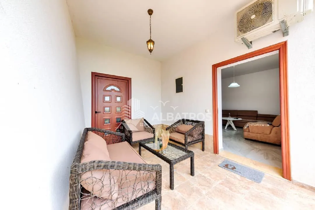Covered terrace furnished with a seating set facing the entrance door.