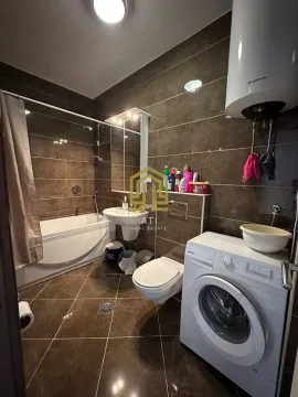 Kupatilo obloženo keramičkim pločicama sa kadom i veš mašinom. - image 9
