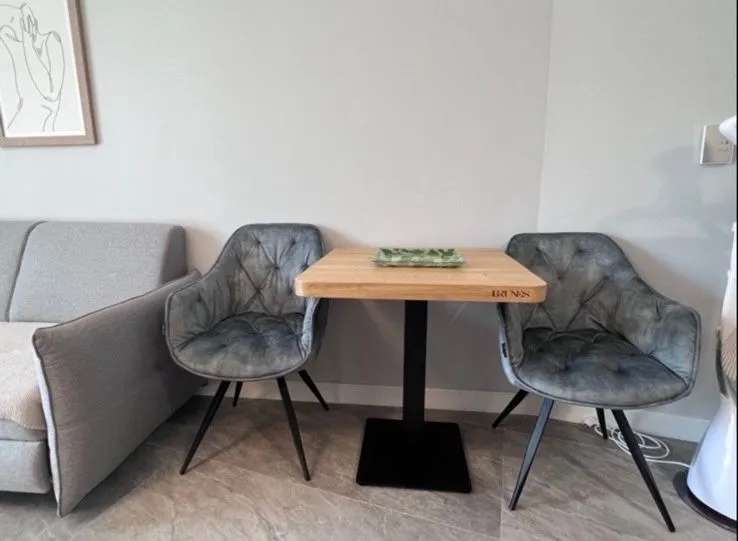 Dnevni boravak sa manjim trpezarijskim stolom i tapaciranim stolicama.