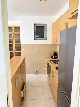 Small kitchen with wooden cabinetry and built-in appliances. - image 7