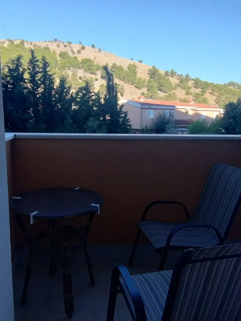 Balcony with outdoor seating and a view of the nearby hill.