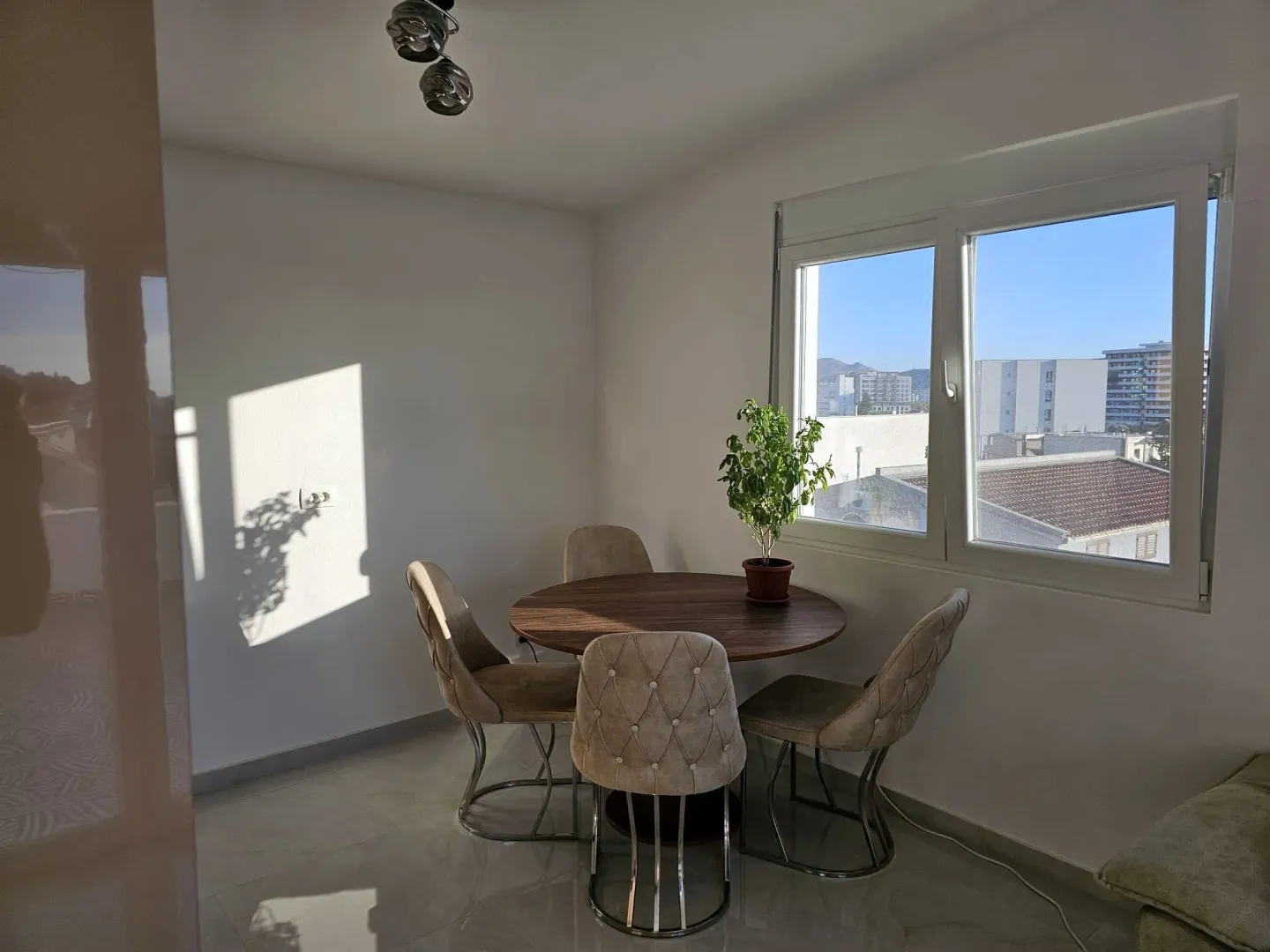 Dining area with a round table, four chairs, and a window with a city view.