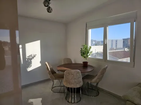 Dining area with a round table, four chairs, and a window with a city view. - image 5