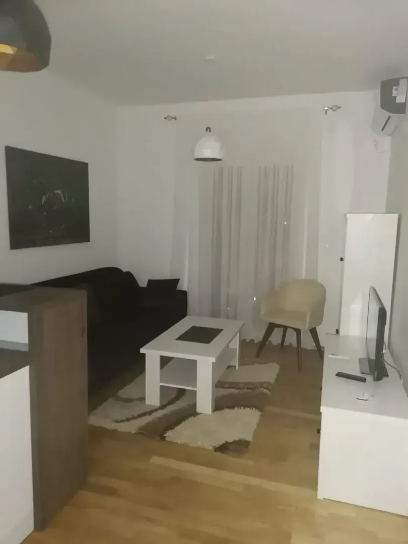 Dnevna soba sa garniturom, stočićem i televizorom.