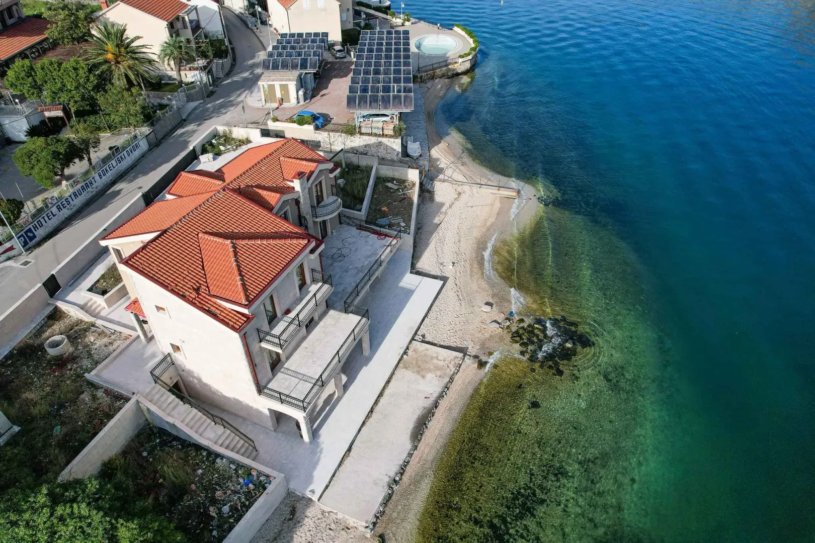 Pogled iz vazduha na kuću sa crvenim krovom pored mora.