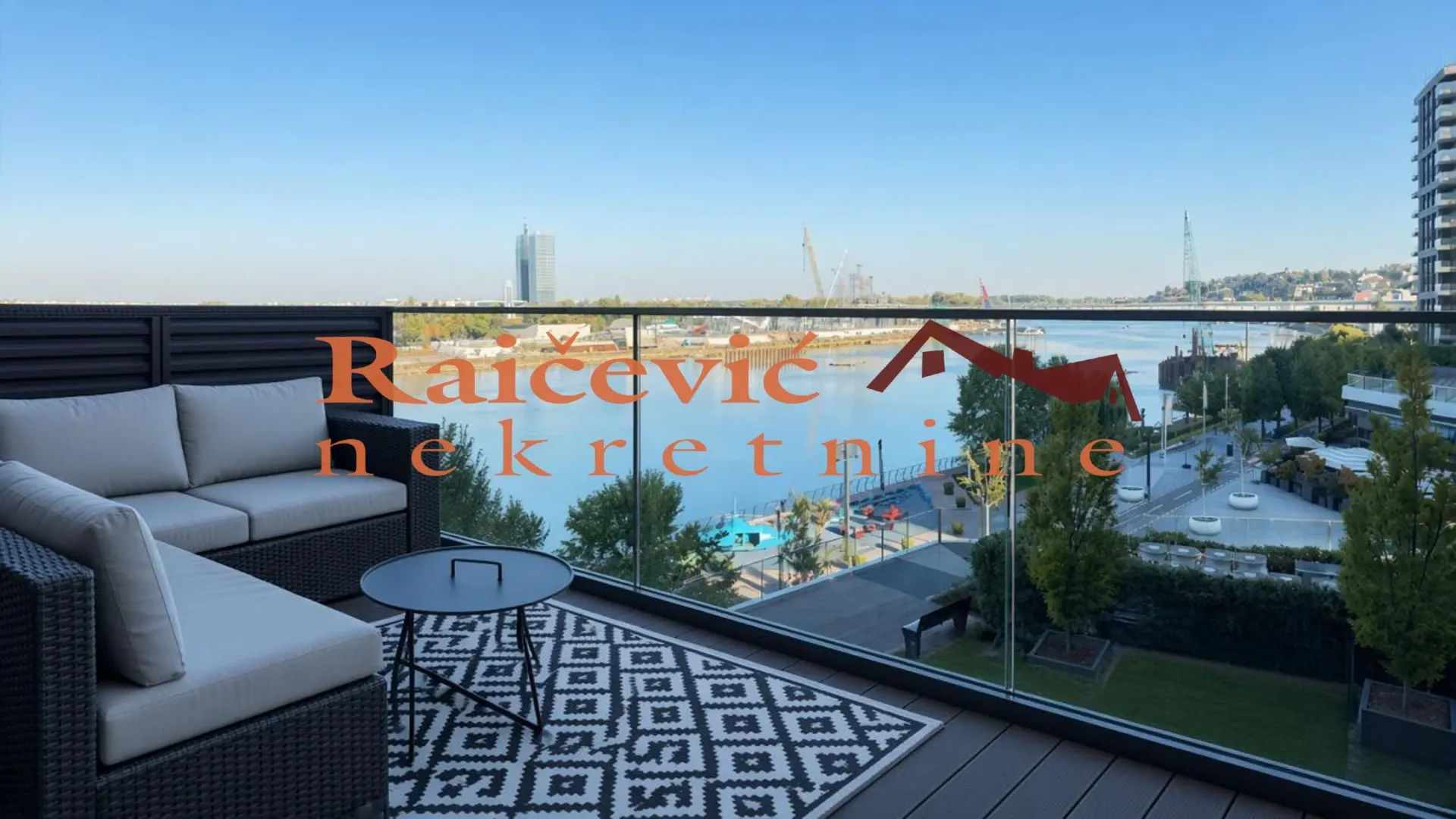 Nameštena terasa sa garniturom za sedenje i pogledom na reku.