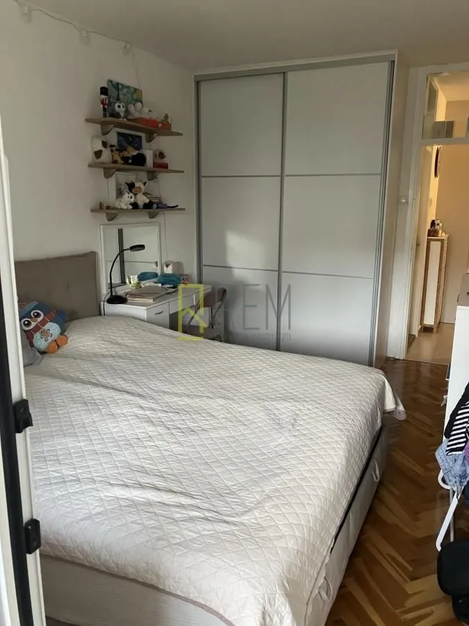 Namještena spavaća soba sa bračnim krevetom i ugradnim ormarom.