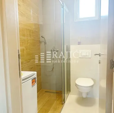 Modern bathroom with a walk-in shower, toilet, and washing machine. - image 10