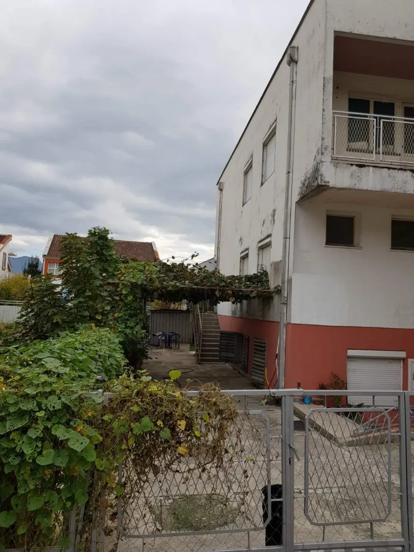 Pogled na dvorište i spoljašnjost kuće sa ogradom.