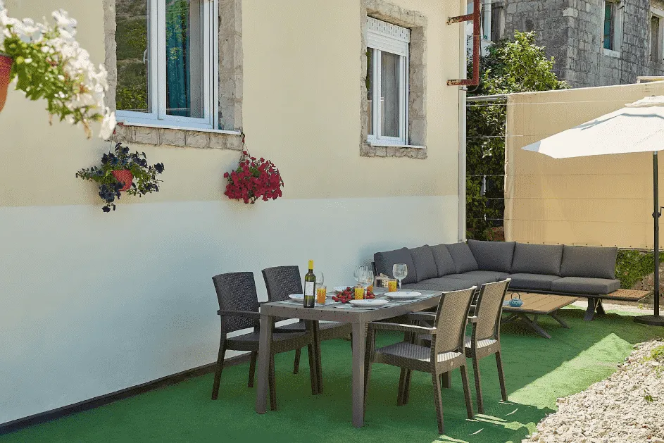 Terasa sa garniturom za sjedenje i trpezarijskim stolom ispred kuće.