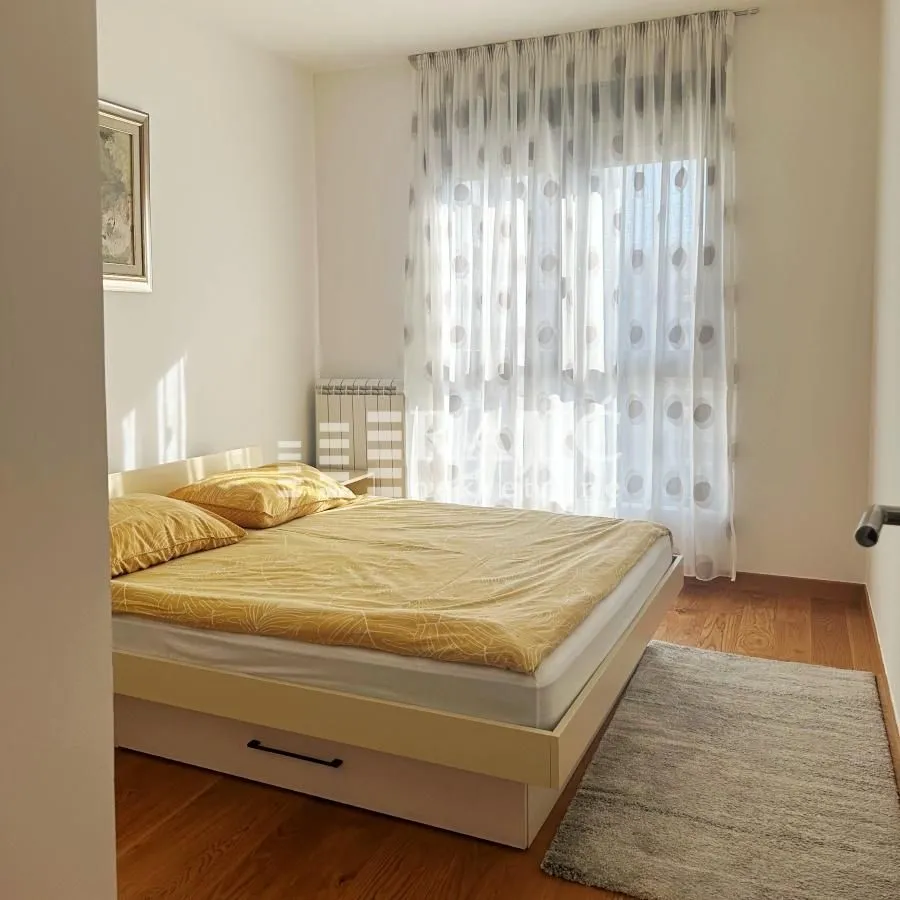 Furnished bedroom with a double bed and curtained window.
