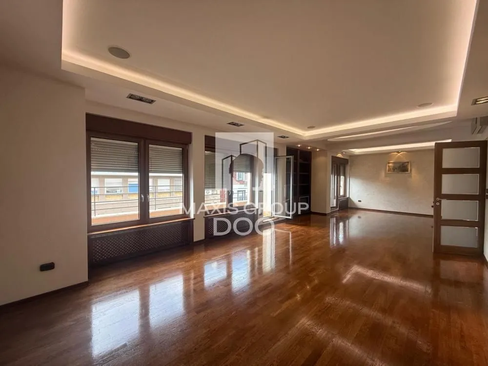 Spacious empty living room with wooden flooring and recessed ceiling lighting.