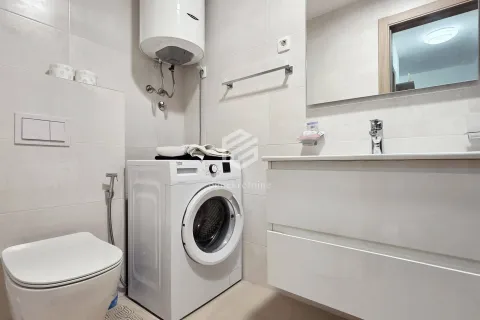Small bathroom with a shower, washbasin, toilet, and washing machine. - image 4