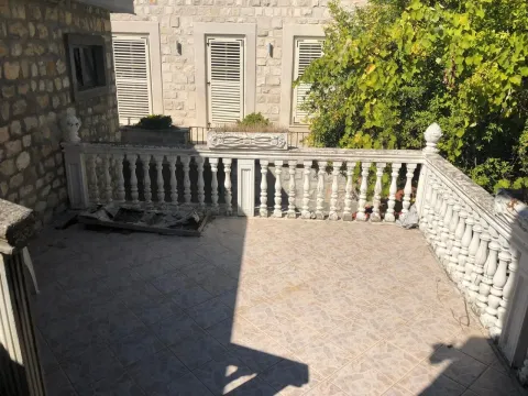 Prostrana popločana terasa sa kamenom ogradom i pogledom na fasadu kuće. - image 10