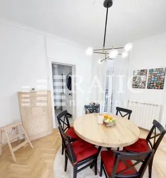 Trpezarija sa okruglim drvenim stolom i crnim stolicama. - image 4