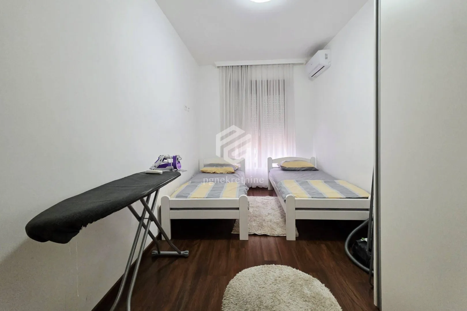 Bedroom with two single beds and an ironing board.