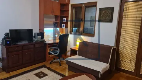 Living room with a desk, TV, and a sofa. - image 2