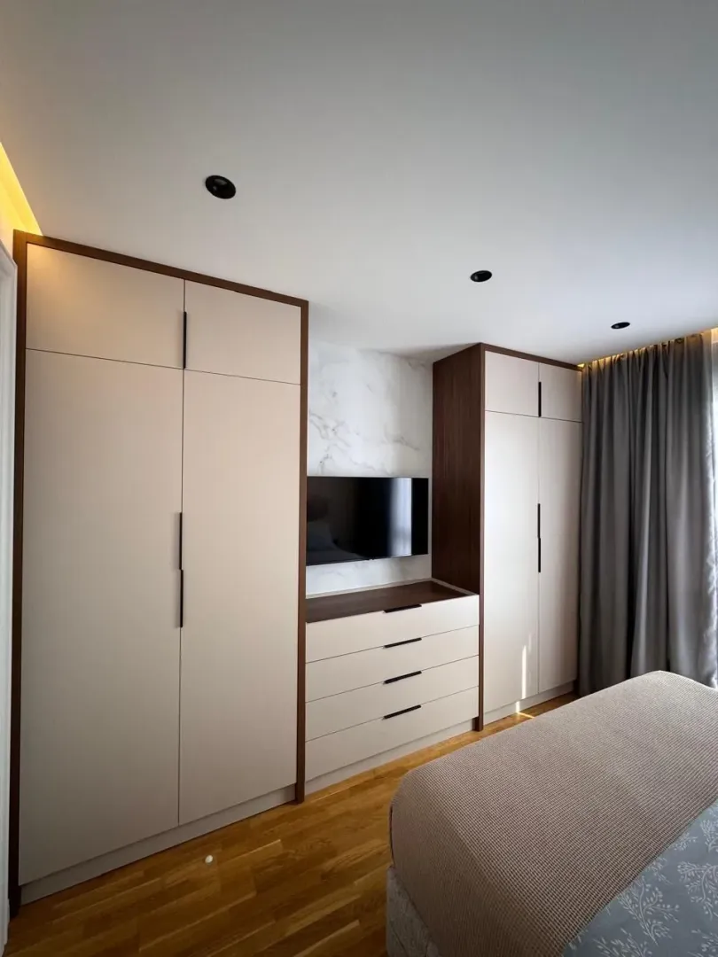 Moderna spavaća soba sa ugradnim plakarima i TV-om.