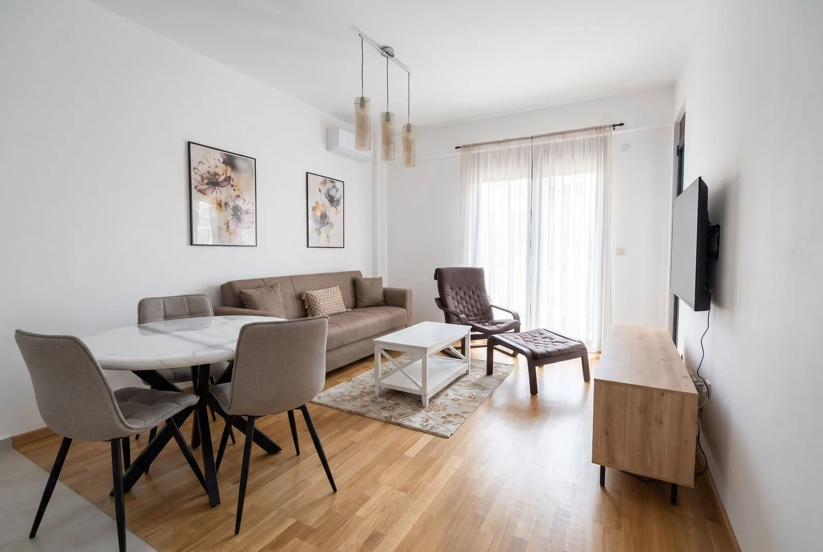 Bright living room with a sofa, dining table, and hardwood floors.