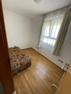 Small bedroom with a bed, parquet flooring, and a window with curtains. - image 4