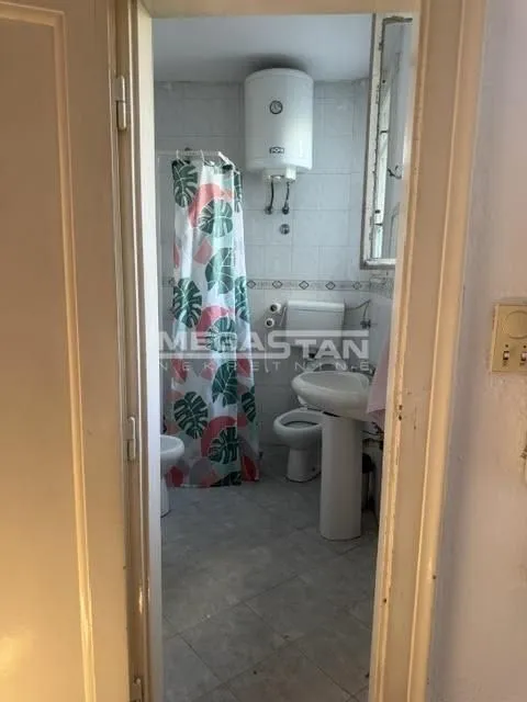 Pogled iz hodnika na kupatilo sa sanitarijama i tuš kabinom.