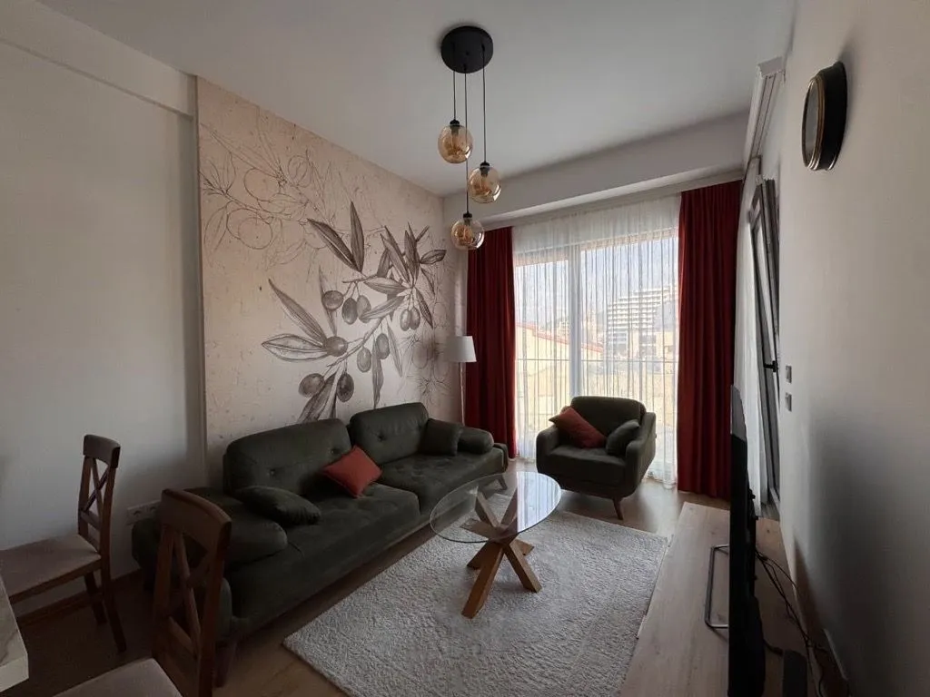 Living room with a sofa, coffee table, and a decorative wall with an olive motif.