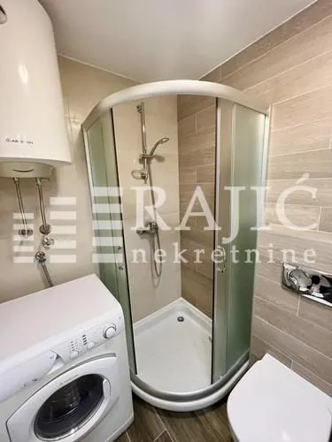 Small bathroom with a shower cabin, washbasin and washing machine.
