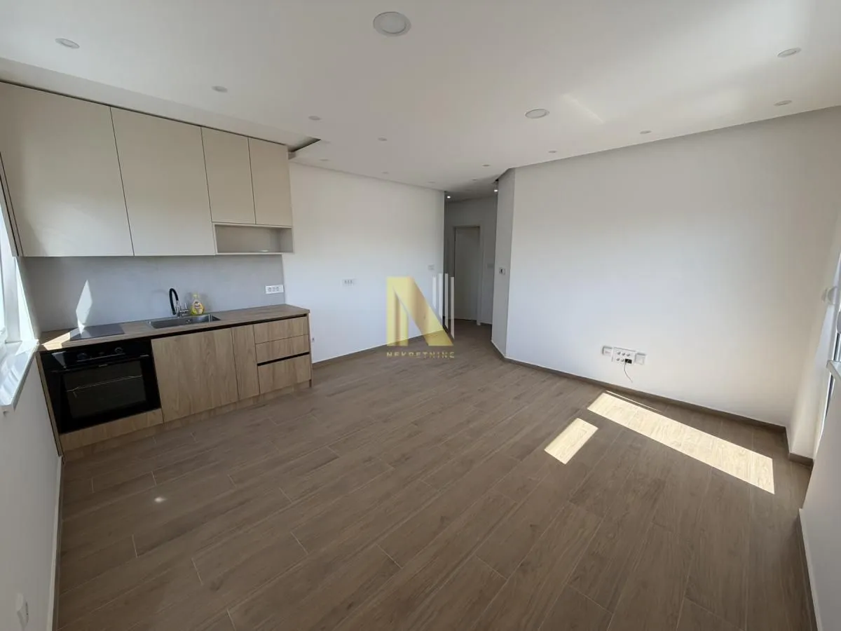 Living room with an integrated kitchen and wooden flooring.