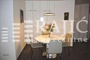 Dining area with a table, chairs, and built-in cabinets. - image 2