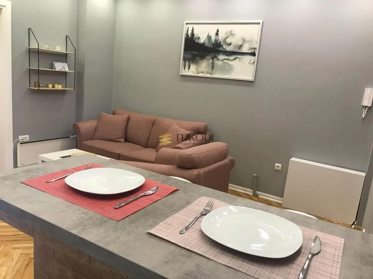 Living room with a sofa and a dining table in the foreground.