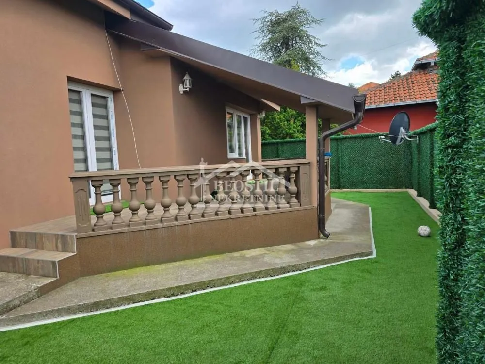Pogled na spoljašnjost kuće sa terasom i uređenim dvorištem.