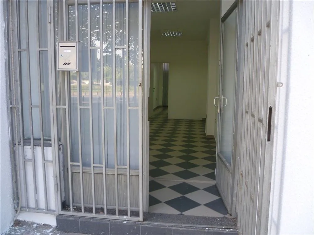 Entrance to a commercial space with protective metal grates and tiled flooring.