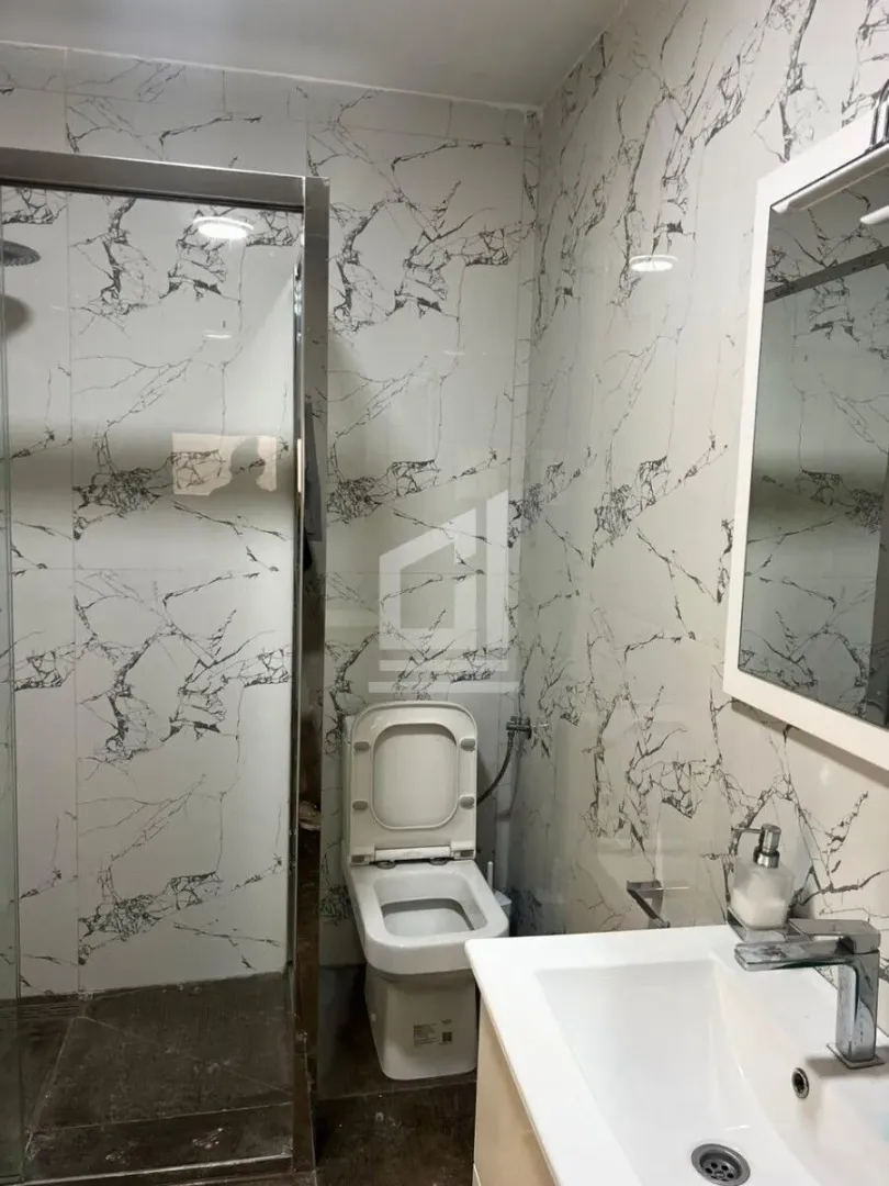 Modern bathroom equipped with a shower cabin, sink, and toilet.