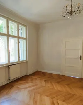 Empty room with parquet flooring, large windows, and a chandelier. - image 4