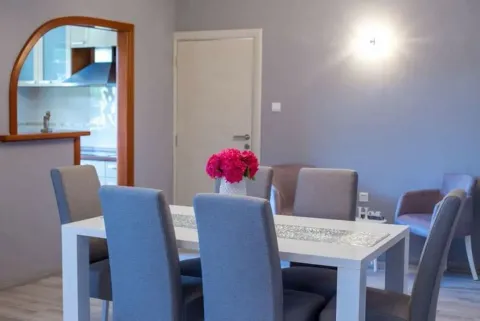 Dining area with a white table and grey chairs, looking through an archway towards the kitchen. - image 8