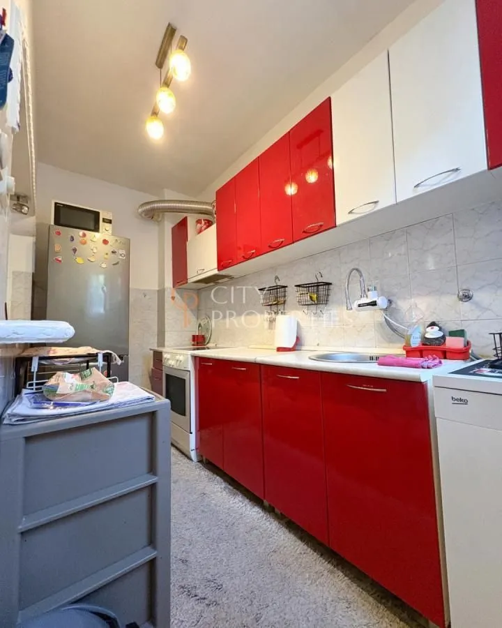 Kitchen with red and white cabinets and white goods.