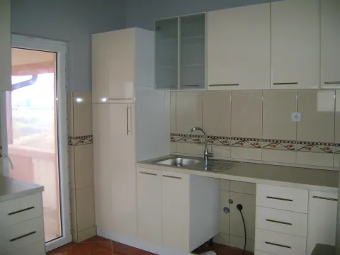 A kitchen with light beige cabinets, tiled backsplash, and a balcony door. - image 7