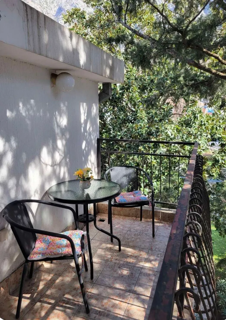 Namješten balkon sa stolom, stolicama i pogledom na zelenilo.
