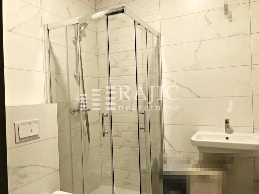 Modernly equipped bathroom with a shower cabin and a sink.