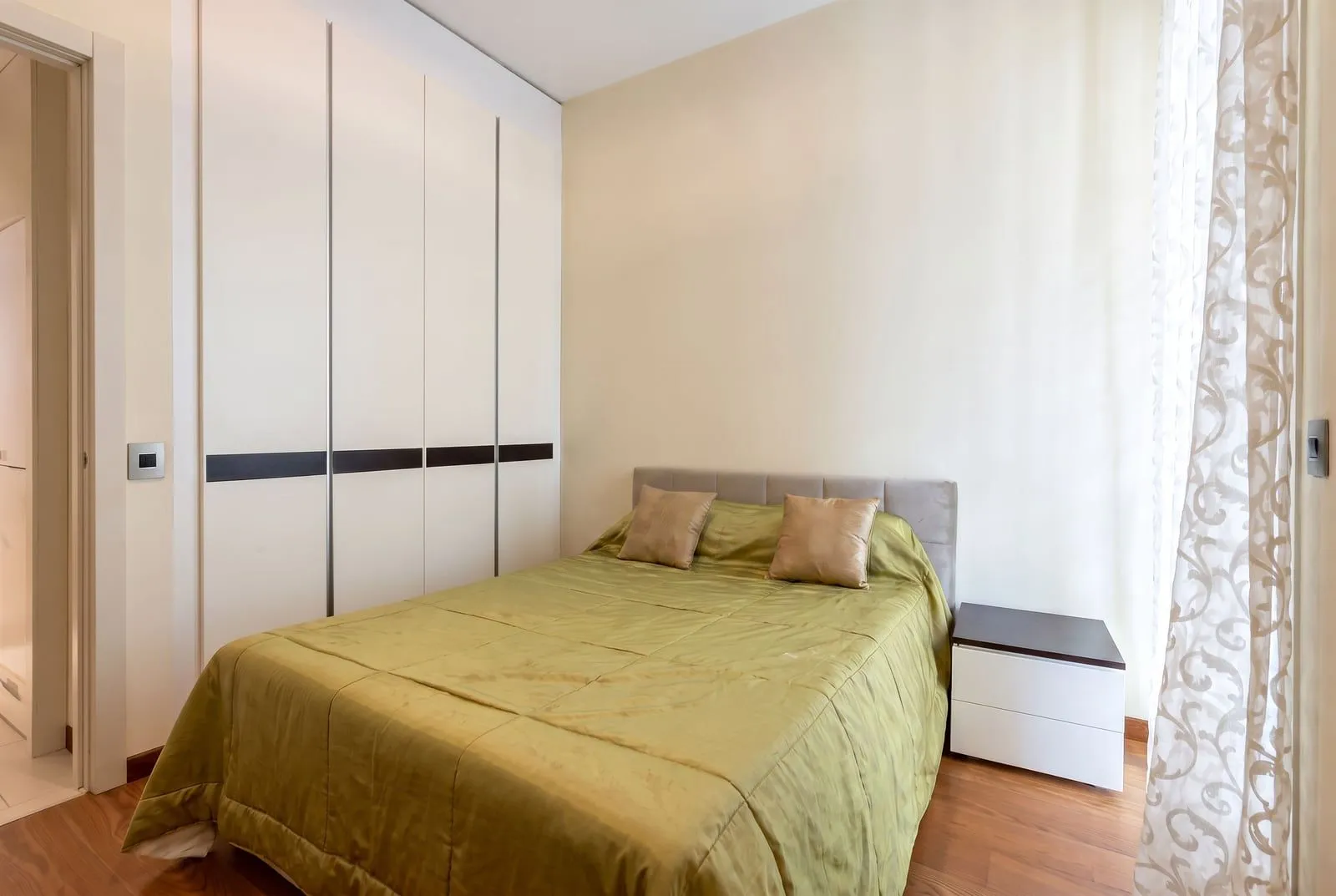 Furnished bedroom with a double bed, wardrobe, and nightstand.